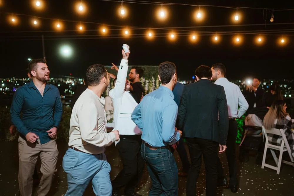 Guests dancing under string lights at an evening reception